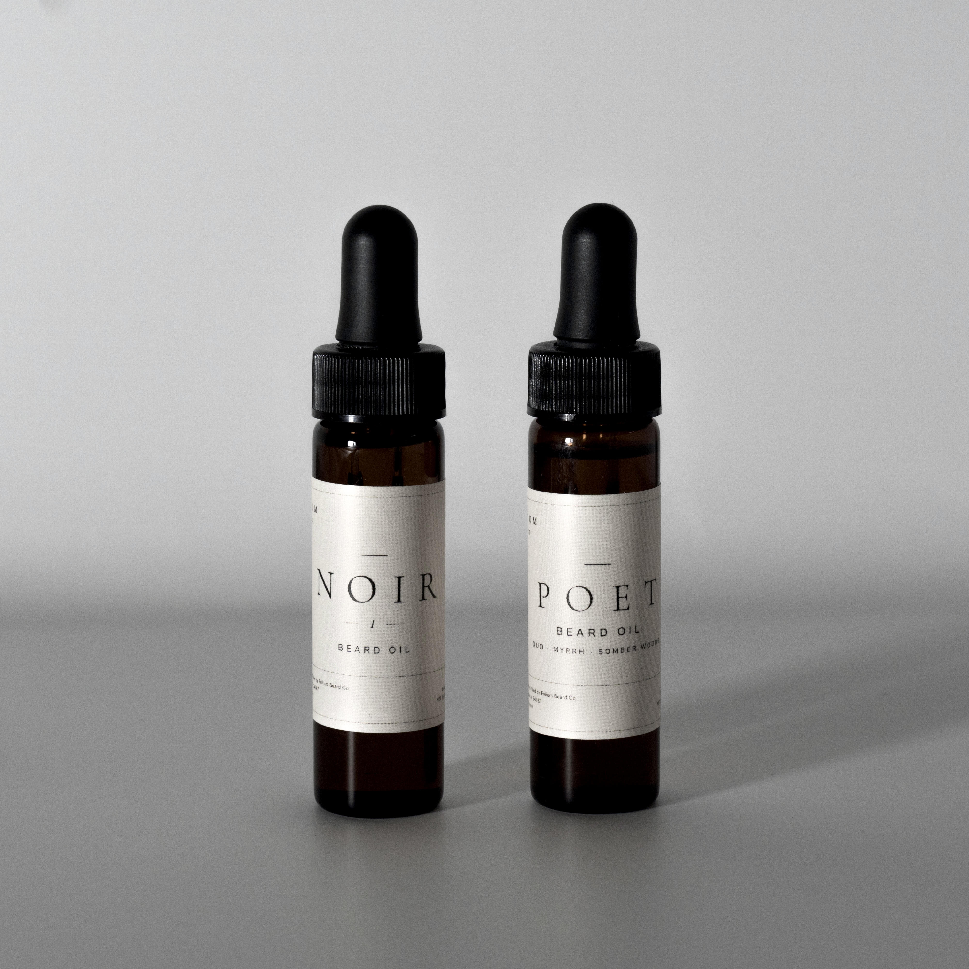 The Poet and NOIR 15 ml beard oils together on a cool grey background.